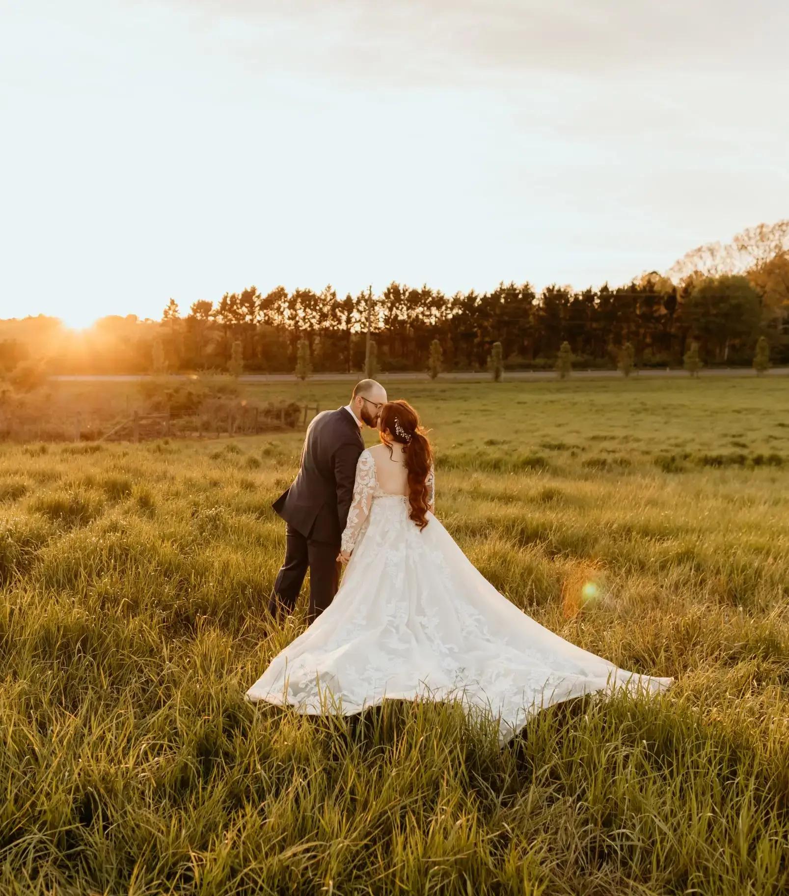 Сouple wearing a white gown and a black suit in the sunset. Mobile image